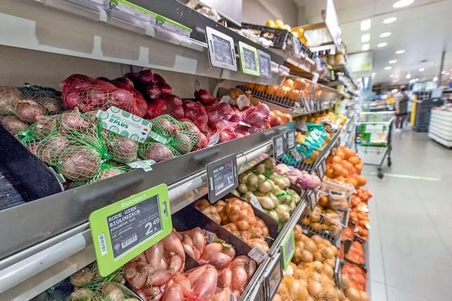 Schap in een supermarkt met biologische uien op de voorgrond.